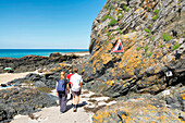 France. Normandy. Department of Manche. Granville. Summer period. Tourists walking at the foot of the cliffs in a dangerous area (risk of falling rocks).
