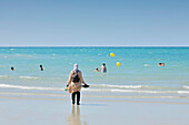 France. Normandy. Department of Manche. Granville during the summer. View from the coast and part of the beach. Young veiled Muslim woman watching her children bathe.