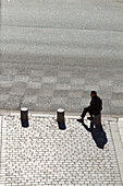 Frankreich,Paris,75,9. Arrondissement,Boulevard Haussmann; Mann sitzt auf einem Betonpfeiler.