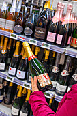 Blonde Frau beim Einkaufen im Supermarkt während einer Weinmesse. Champagner Moët et Chandon