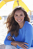 Woman in blue jumper sitting on the beach