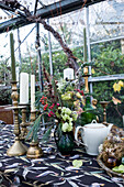 Festliche Tischdekoration mit Kerzen, Blumenstrauß und Teekanne im Wintergarten