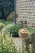 Strohhut auf Gartenzaun, blühende Sommerblumen