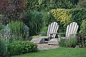 Zwei Liegestühle aus Holz im begrünten Garten