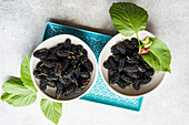 Mulberries with leaves in small bowls