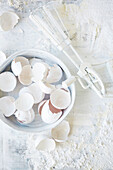 Egg shells and hand whisk on a floured worktop