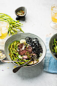 Wild asparagus salad with steak strips, black pasta and chimichurri