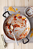 Empty pan with leftovers from a tomato dish