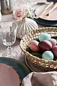 Easter table setting with coloured eggs in a wicker basket