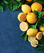 Whole and sliced lemons with leaves on a dark blue background