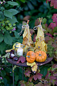 Herbstliche Dekoration mit Kürbis, Äpfeln und Kastanien im Garten