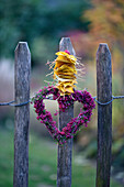 Heather heart with leaves lined up on a wooden fence, autumn decoration