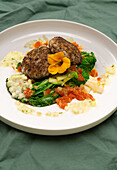 Bean patties on steamed vegetables with flower garnish