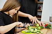 Mother and daughter cutting cucumber