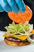 Chef placing tomato slice onto burger