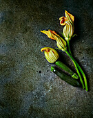 Courgette flowers and baby courgettes on a stone slab