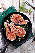 Raw salmon steaks with spices in a pan