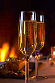 Glasses of champagne in front of a fire