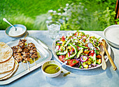 Summer salad with grilled chicken skewers and flatbread