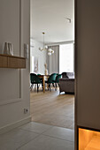 Dining area with green velvet chairs, light-coloured wooden table and modern pendant light