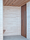 Covered entrance with light-coloured brick wall and wooden ceiling