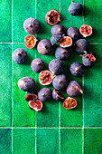 Whole and halved figs on a green background