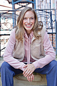 Young woman in hoodie, fur waistcoat and blue chinos