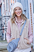 Young woman in hoodie, fur vest and blue chinos