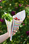 Bunte Tüten aus Wachstüchern mit Petersilie und Kirschen im Garten