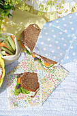 Sandwiches in homemade bread bags made of oilcloth on a picnic blanket
