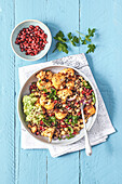 Bowl with spicy grains, roasted cauliflower and pomegranate seeds