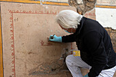 Archaeologist excavating ancient Roman food stand, Pompeii, Italy