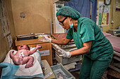 Nurse weighing newborn baby