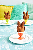 Eggs in colourful egg cups with fabric bunny ear egg warmers