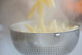 Draining penne pasta into a colander