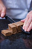 Close up of a chef's hands cutting a chocolate block