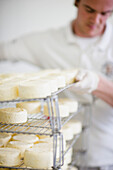 Man lifting up a rack lined up with cheeses