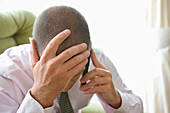 Close up of Businessman with Head in Hands Using Cell Phone