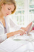 Woman Using Tablet Computer whilst Sorting Out Bills