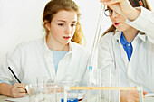 Schulmädchen experimentieren im Chemieunterricht mit dem pH-Wert einer alkalischen Säure