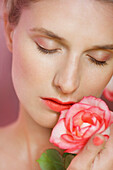 Close up of Young Woman Holding Rose to her Lips