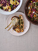 Still life table top view healthy Mediterranean meal of grilled salmon with pesto, leeks, salads