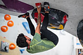 Young man in his twenties climbing on a climbing wall indoors