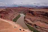 Touristen parken am Thelma and Louise Point auf dem Shafer Trail am Colorado River in der Nähe von Moab, Utah. Der offizielle Name ist Fossil Point, aber es ist der Schauplatz der berühmten Szene am Ende des Films Thelma und Louise". Rechts, auf der anderen Seite des Flusses, liegt das Bears Ears National Monument. Hinweis: Die Drohne wurde legal außerhalb der Grenzen des Monuments geflogen."