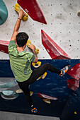 Junger Mann in den Zwanzigern beim Klettern an einer Kletterwand in einer Halle