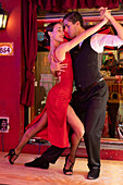 An attractive young couple dances the tango on El Caminito in the La Boca barrio of Buenos Aires, Argentina.