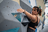 Junger Mann in den Zwanzigern beim Klettern an einer Kletterwand in einer Halle