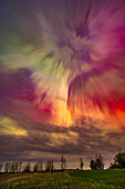 An outburst of a substorm during the great May 10, 2024 display of Northern Lights, here creating an overhead corona with rays converging to the magnetic zenith (south of the true zenith), and amid clouds. The rays show a rich mix of oxygen greens and reds, as well as nitrogen blues blending to create purples. Some green and red are mixing to make yellows.