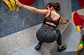 Young man in her twenties climbing on a climbing wall indoors