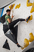 Young man in his twenties climbing on a climbing wall indoors